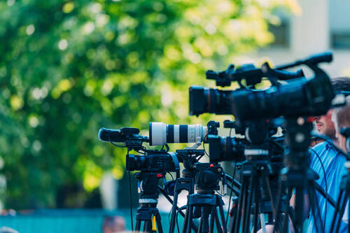 Cameras at a media conference outdoors.